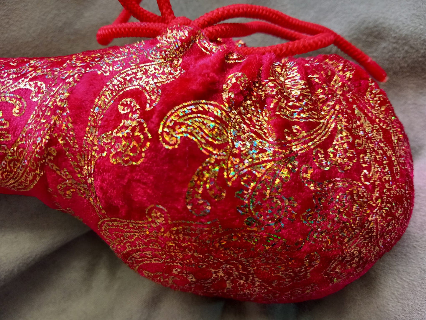 Penissocke aus elastischem roten Lycra Samt mit goldenen Hologramm Ornamenten. Vorne geschlossen mit Gummibändel zum Schnüren