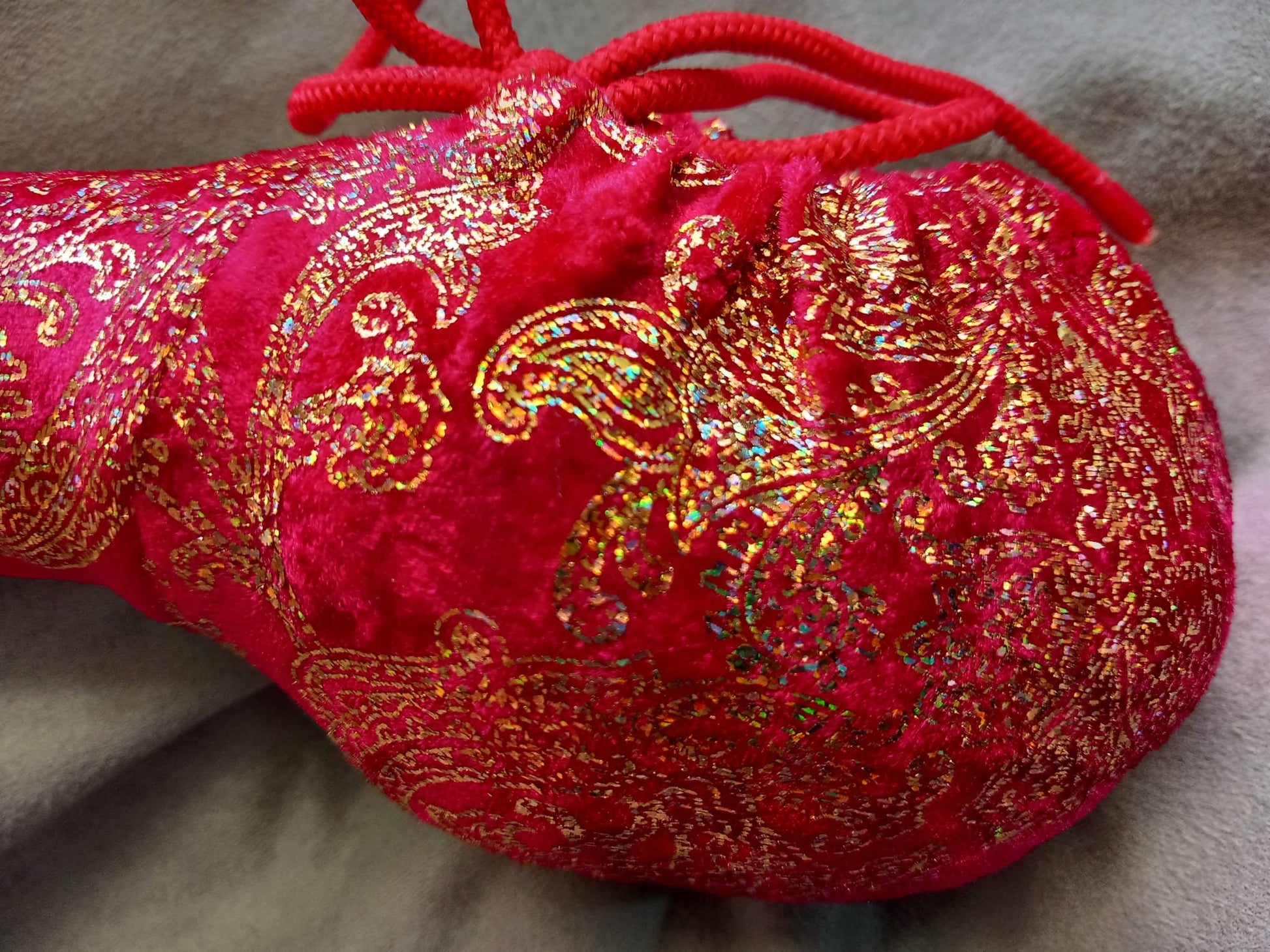 Penissocke aus elastischem roten Lycra Samt mit goldenen Hologramm Ornamenten. Vorne geschlossen mit Gummibändel zum Schnüren