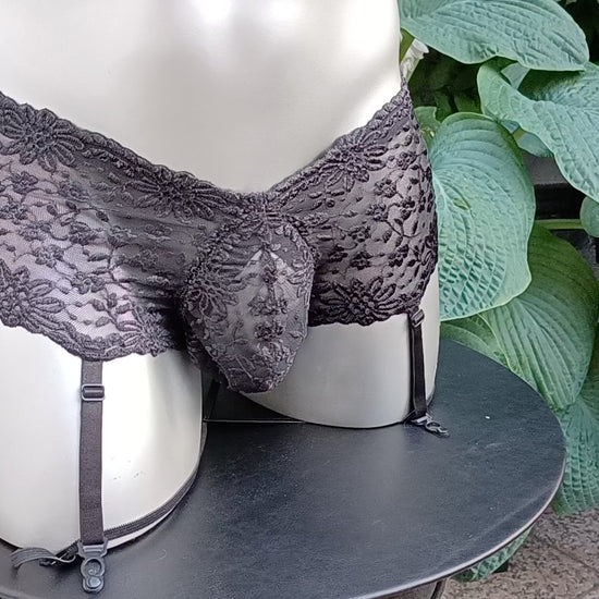 Herren Strapse aus schwarzer elastischer Spitze. Der Tanzgürtel ist ouvert mit Push-Up Suspensorium und Cockring